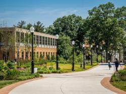 Students walking by Sprague Library and Life Hall on a summer day.